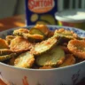 A plate of crispy fried pickles served with dipping sauce.