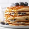Fluffy gluten-free blueberry pancakes topped with fresh blueberries and syrup.