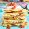 Breakfast quesadilla with bacon, melty cheese, and scrambled eggs on a plate.