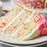 Moist funfetti cake topped with creamy vanilla frosting and colorful sprinkles.