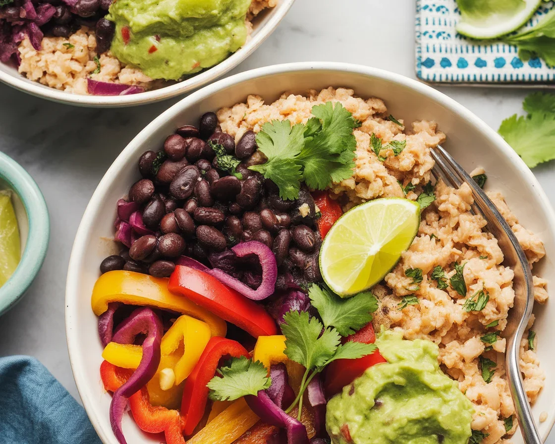 Vegan cauliflower rice burrito bowl topped with black beans, grilled peppers, and guacamole.