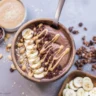 Protein smoothie bowl with peanut butter, bananas, and nutritious toppings.