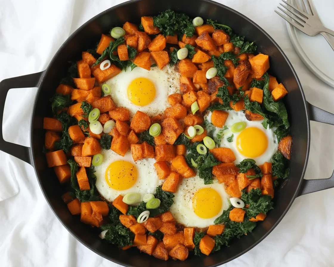 Sweet potato breakfast hash with eggs, kale, and bell peppers on a plate.