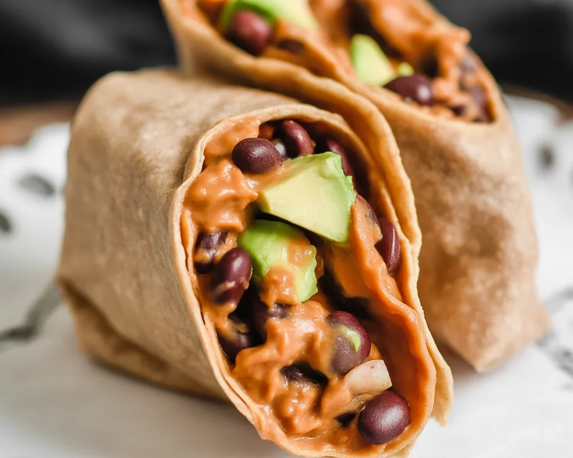Healthy sweet potato and black bean breakfast burrito on a plate with fresh toppings.